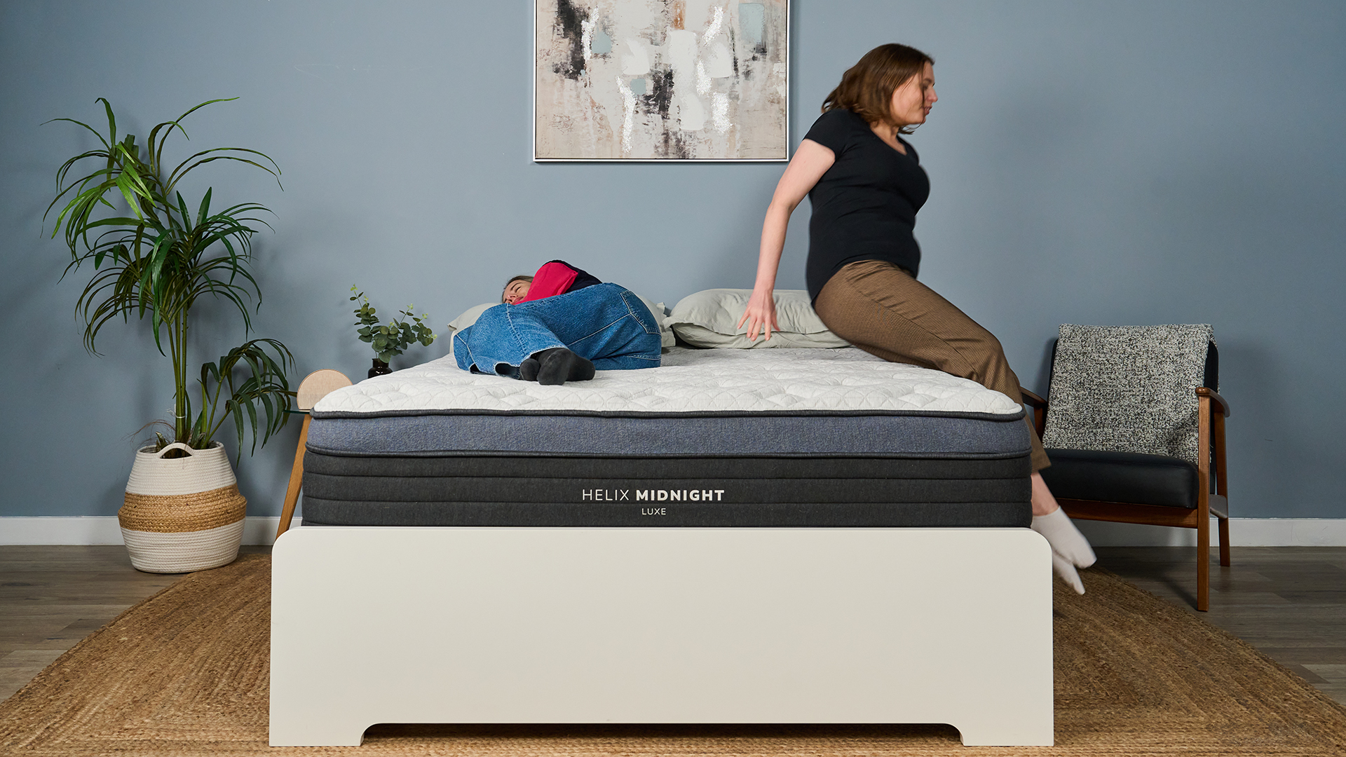 Tester Nicola Appleton lies on her side on the Helix Midnight Luxe Mattress as tester Ruth Jones jumps on the mattress, to test the motion isolation