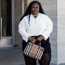 woman wearing white shirt, black pants, and plaid bag