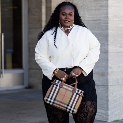 woman wearing white shirt, black pants, and plaid bag