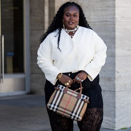 woman wearing white shirt, black pants, and plaid bag