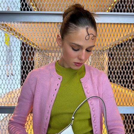 a woman wearing a pink cardigan layered over a green sweater