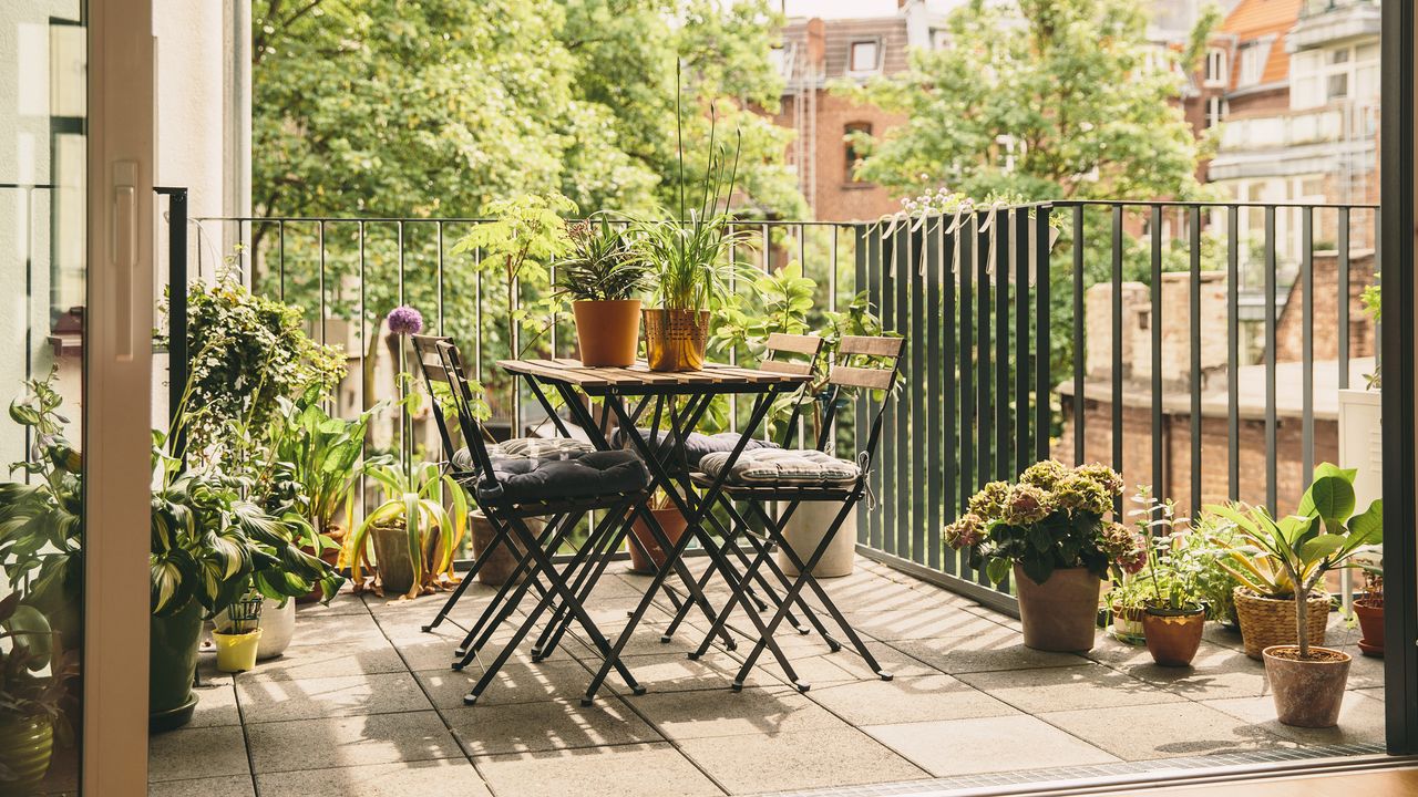 Wooden bistro table in a balcony plants garden with lots of container plants