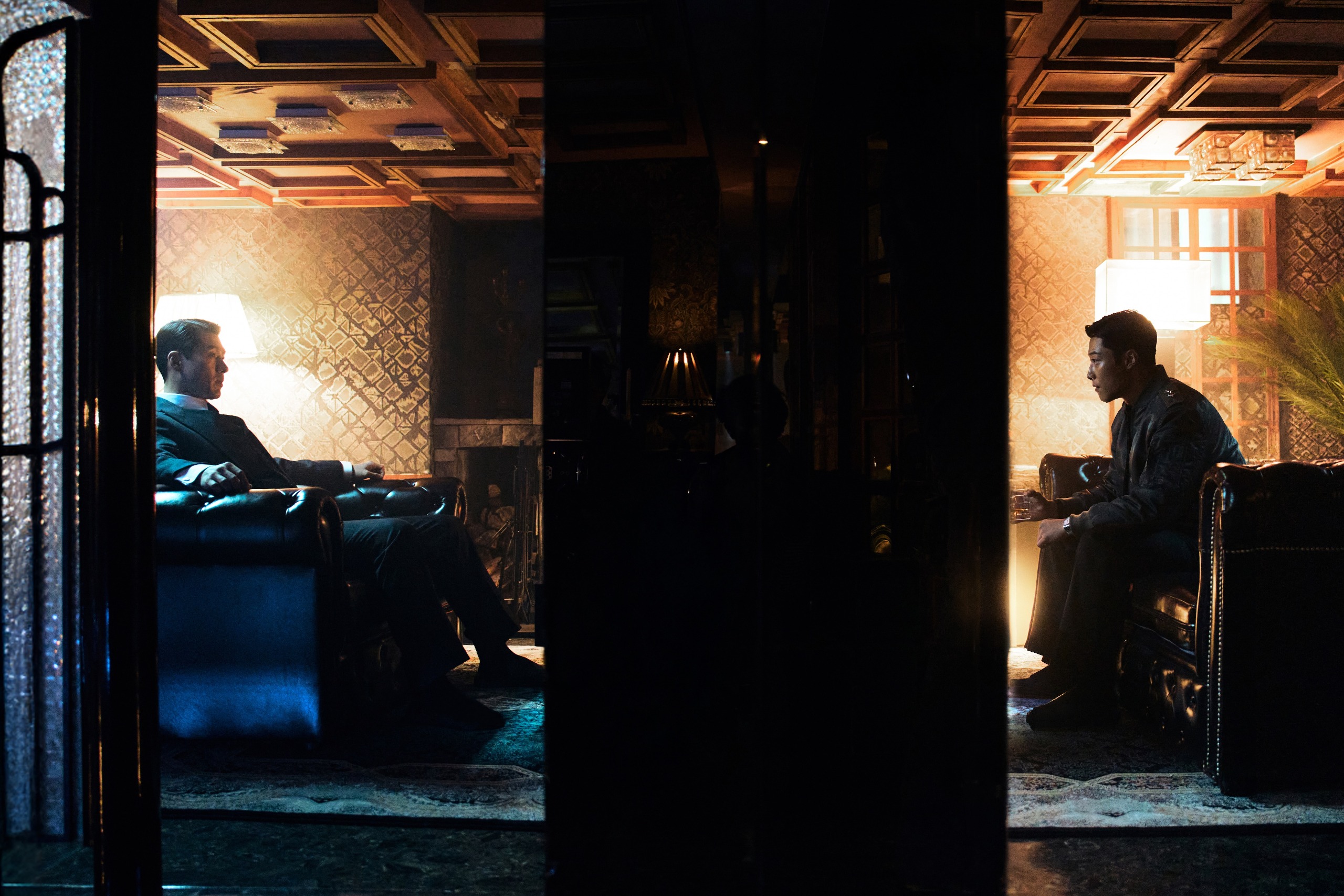 Two men (l-r, Hyun Bin as Baek Kitae and Woo Do-hwan as Baek Kihyun) sit in armchairs on each side of a room with a decorative wall in the middle. A still from Hulu's 'Made in Korea' season 2.