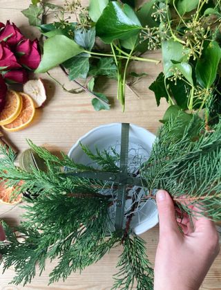 Christmas table centerpiece step by step with foliage placed in bowl