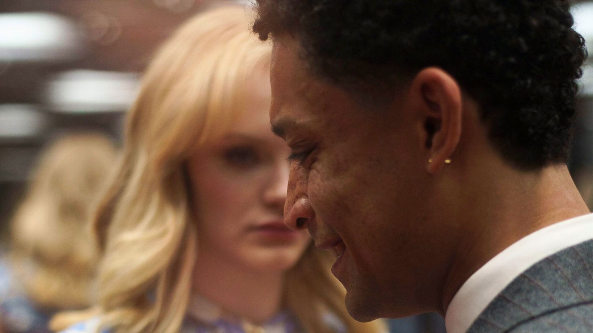 A man laughs while half a woman's face can be seen in the background