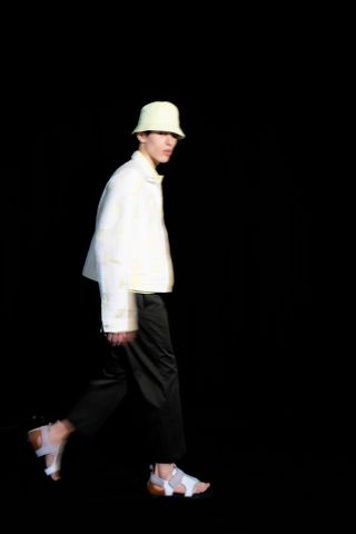 Man on black background wearing outfit and hat by Hermès