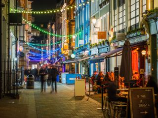 Gente caminando por pubs y bares en el Soho de Londres por la noche