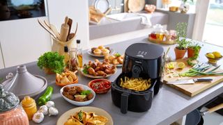 A Phillips air fryer surrounded by food that was cooked in it