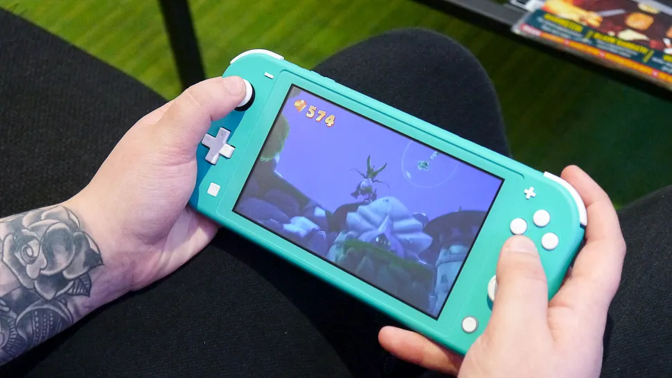 The Nintendo Switch Lite being played while sat at a sofa.