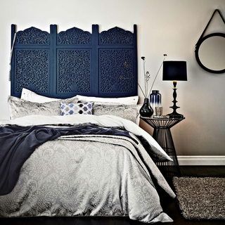 bedroom with white wall blue designed bed and black flooring