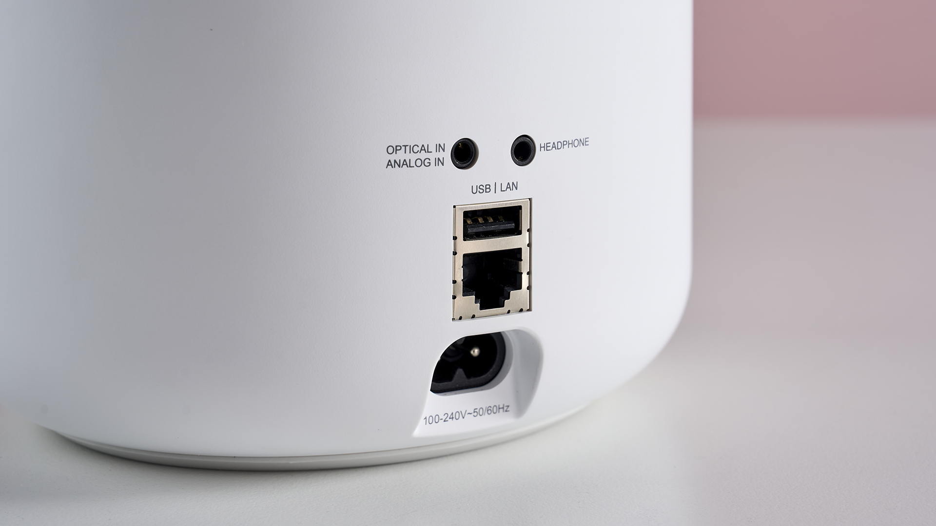 A closeup of the rear of the Bluesound Pulse M showing its power and Ethernet ports, as well as analog and digital optical inputs.