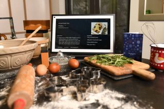 An Amazon Alexa show on a kitchen countertop showing baking ingredients in the foreground