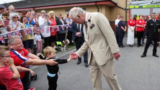 Prince Charles, Prince of Wales greets a child during his visit to Morecambe fire station on July 8, 2022