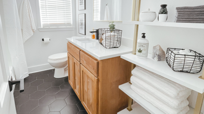 White bathroom with black tiling, large wooden cabinet and white furnishings