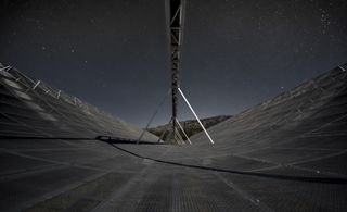 CHIME radio telescope (seen at night here) recently detected rare, low-frequency bursts of energy from deep in the universe. Astronomers are eagerly searching for an explanation.