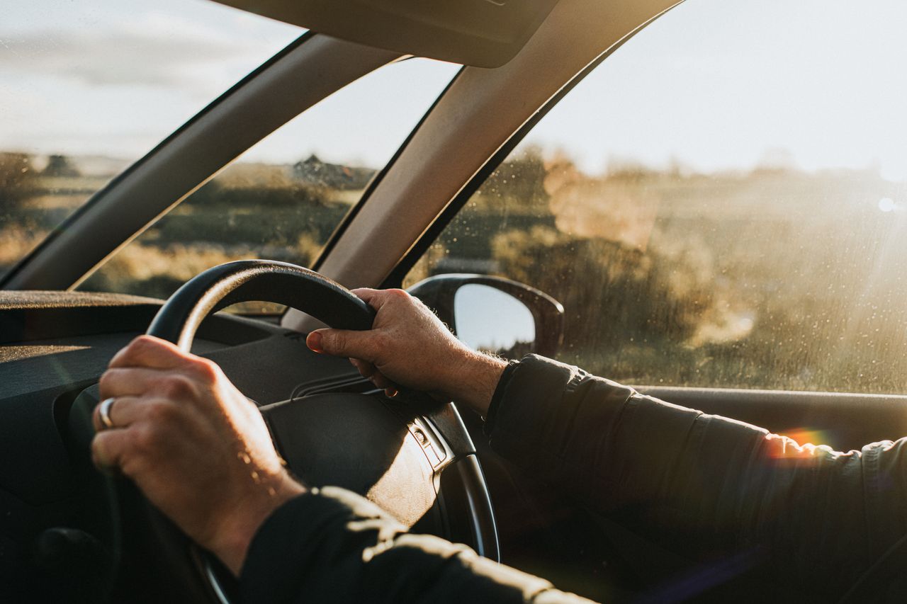 Person holds steering wheel while driving in car