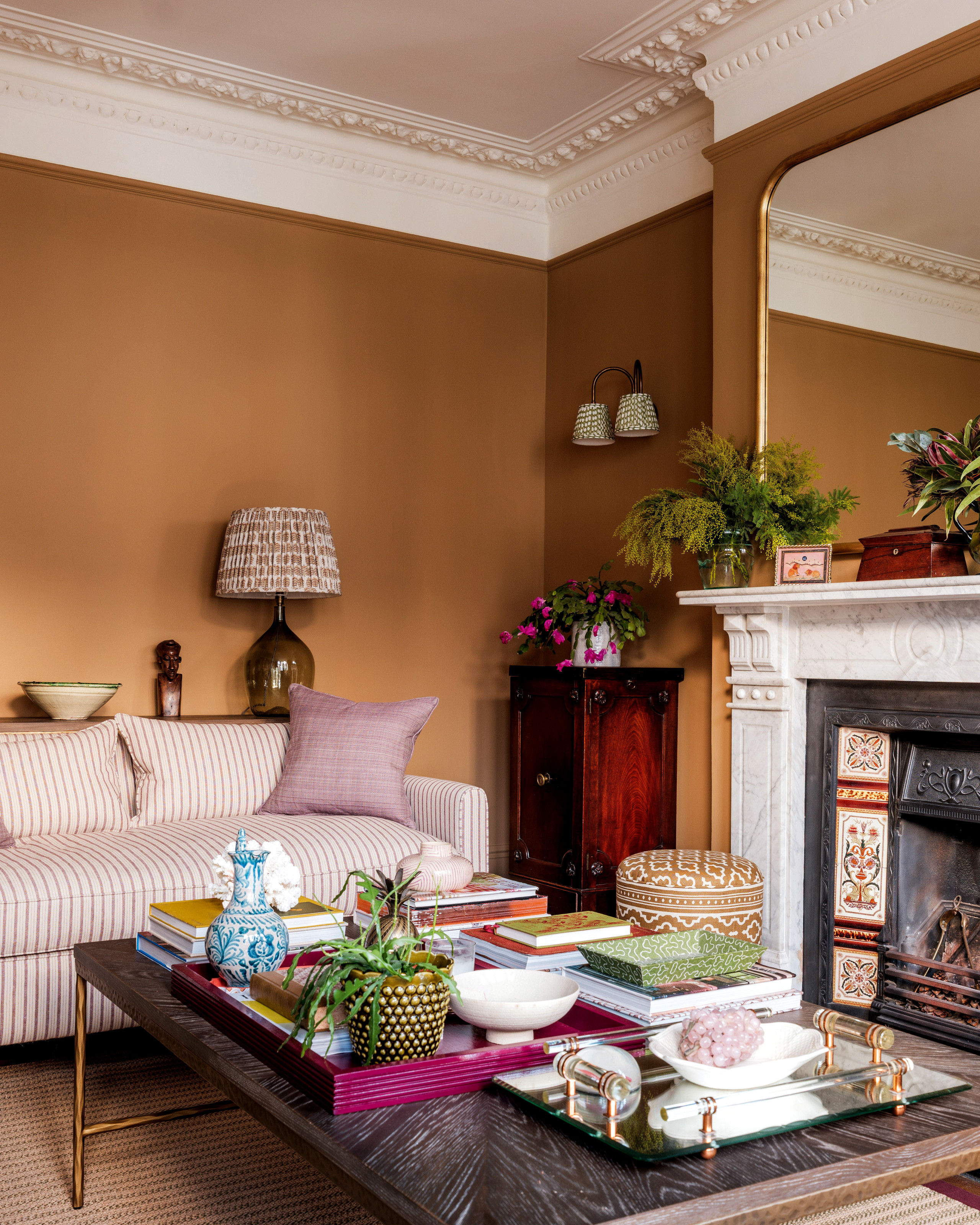 Orange living room with striped sofa, stone and brass coffee table and white marble fireplace