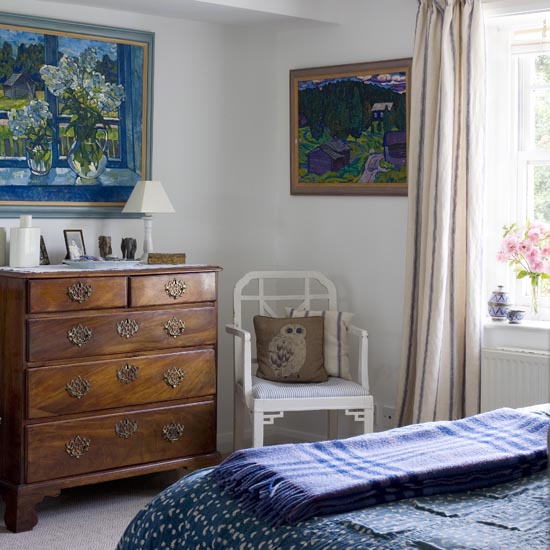 master bedroom with chest of drawer and white chair