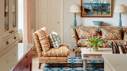 neutral snug at the end of a cozy kitchen by Yellow London with and orange floral couch and a blue folk weave rug