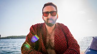 Nick Cage sits in the sun in a robe in The Unbearable Weight of Massive Talent