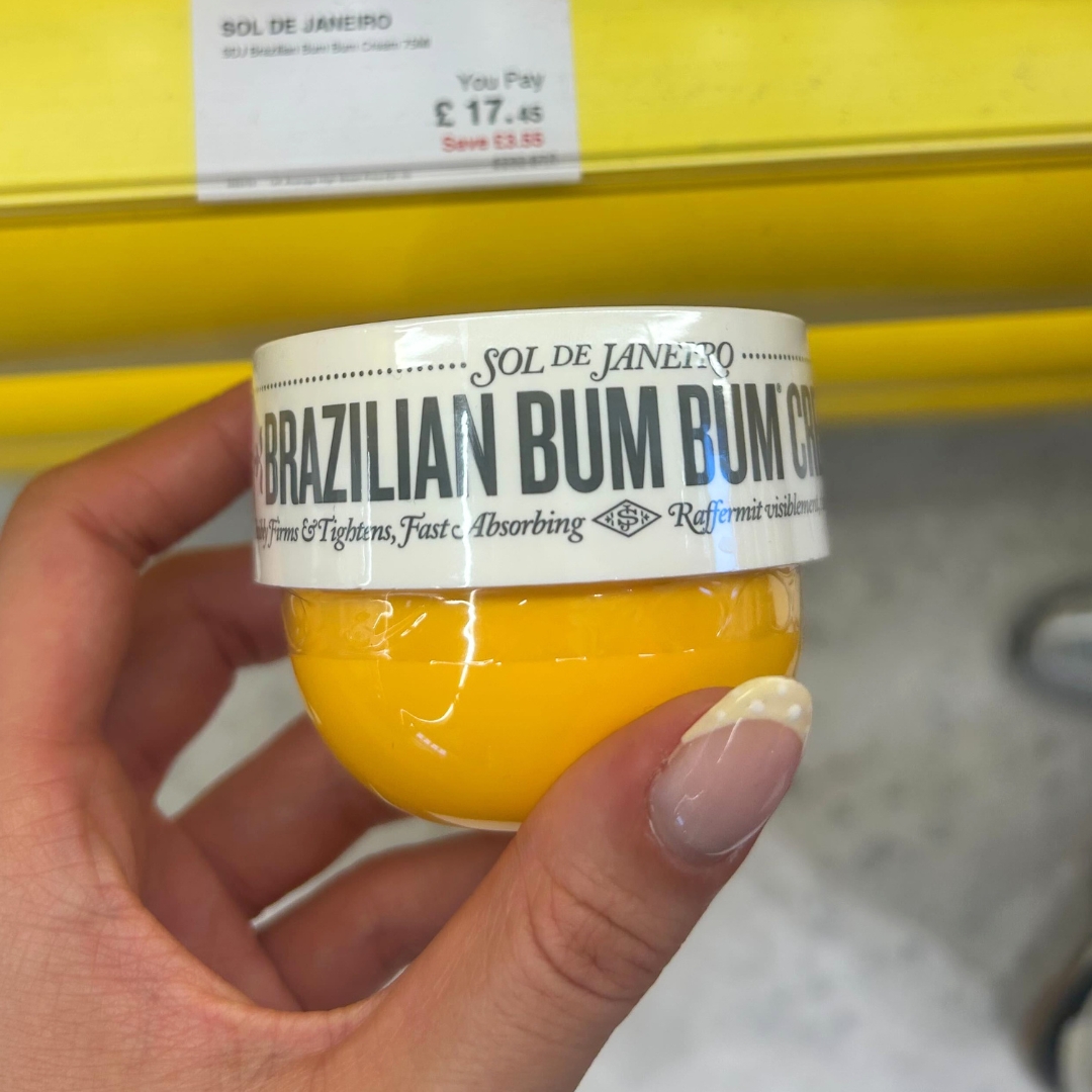 Hand holding tub of Sol de Janeiro Brazilian Bum Bum Body Cream in World Duty Free