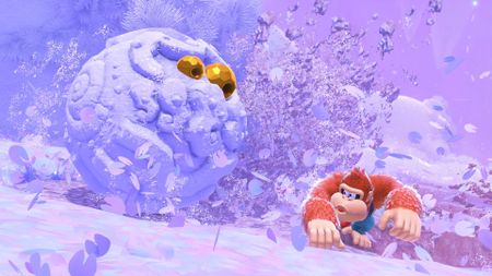 Donkey Kong Bananza screenshot of Donkey Kong on a snowy landscape in front of a big snow ball with golden eyes 