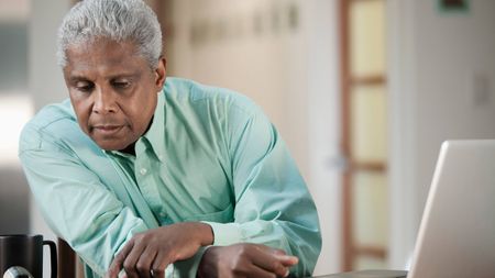 Retiree at table with open laptop looking at a calendar