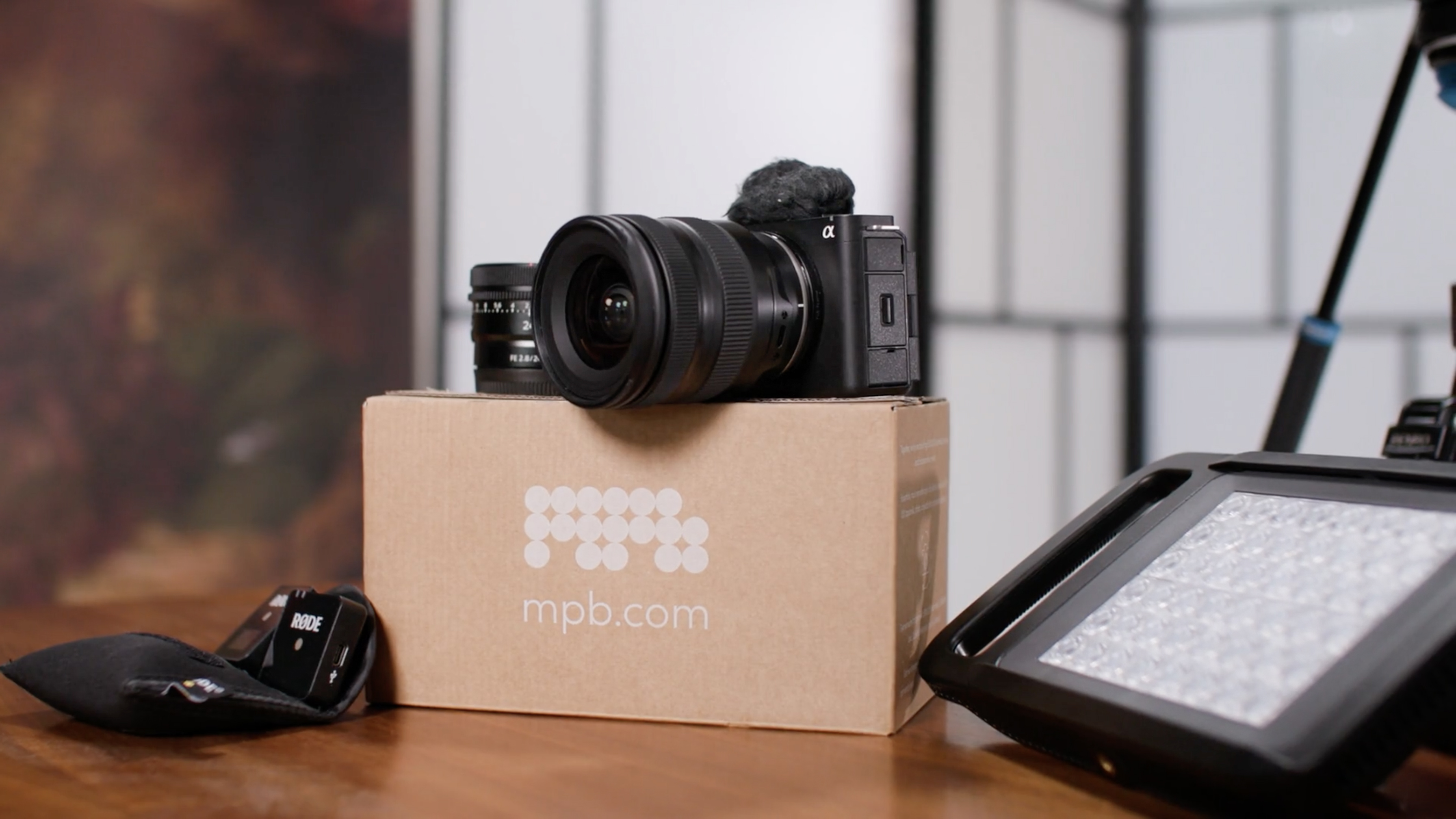 Second-hand camera and equipment, with packaging from retailer MPB, on a wooden surface