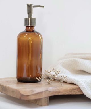 amber glass soap dispenser on wooden tray