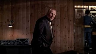 Gert Frobe stands laughing in his secret lair in Goldfinger.