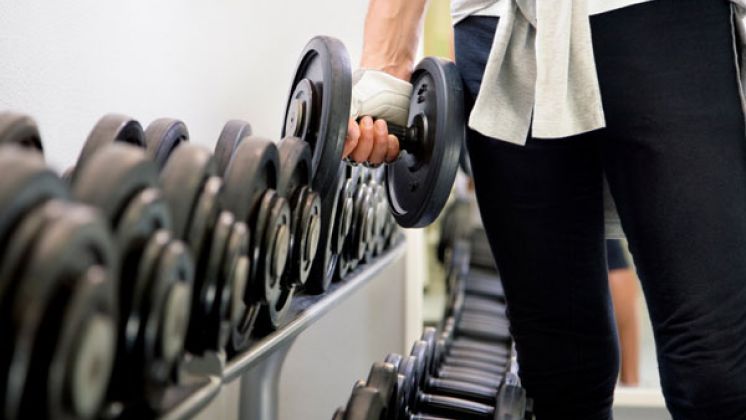 Man holding dumbbell next to dumbbell rack in a gym