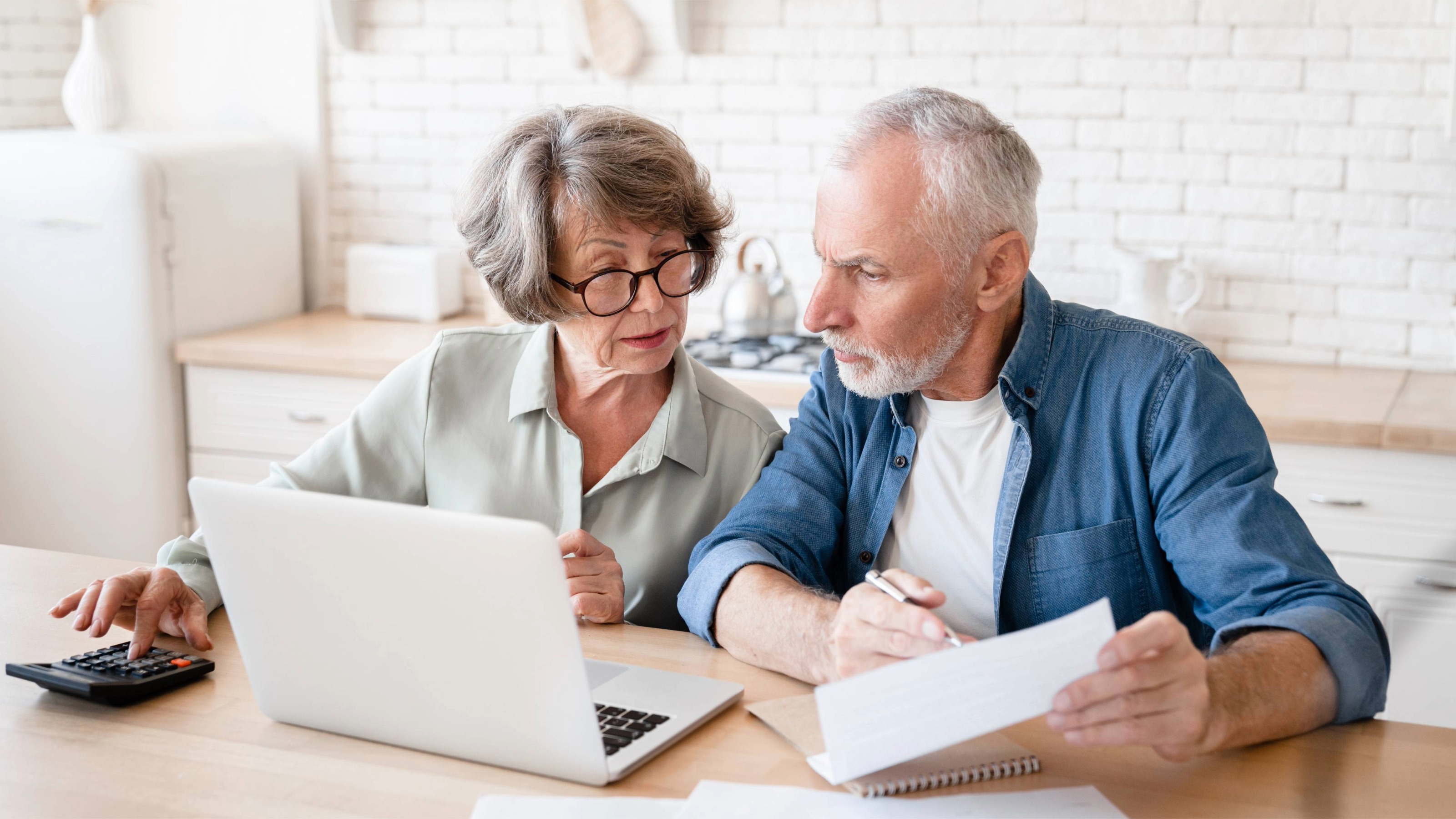 Senior couple making calculations at home kitchen