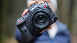A hand holding the Canon EOS R5 C camera in the rain