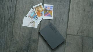 The Fujifilm Instax Mini Link+ on a gray background with instant prints