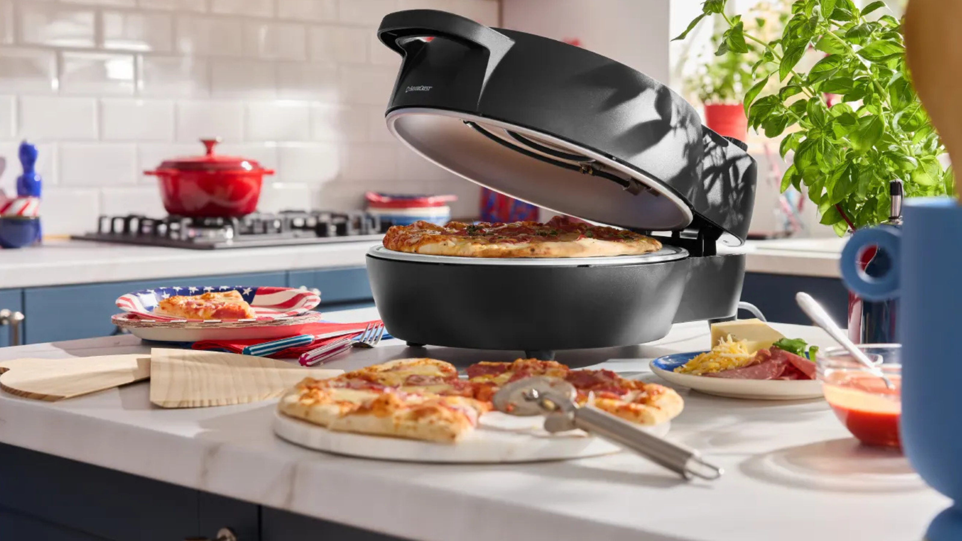 Lidl indoor pizza oven on kitchen island. There is a chopping board with a pizza on top in front.
