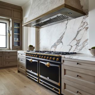 a marble and wood kitchen with a black and brass range cooker