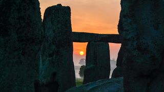 The setting sun peeks through Stonehenge
