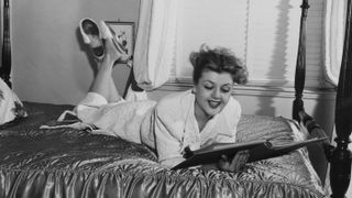 Portrait of actress Angela Lansbury, lying on a hotel bed wearing a bathrobe, circa 1955-1965