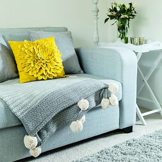 blue sofa with yellow and grey cushion plant on table