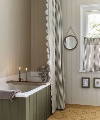 Bathroom with striped, scalloped shower curtain, green bathtub