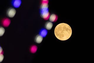 A yellow moon with blurry city lights in the foreground