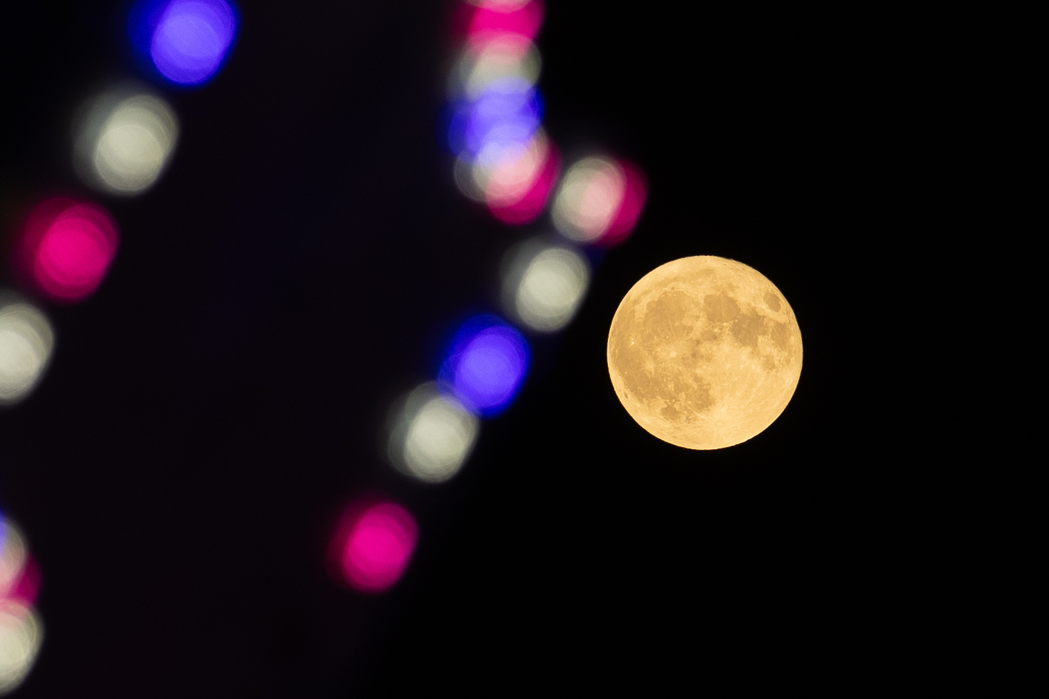 Uma lua amarela com luzes desfocadas da cidade em primeiro plano