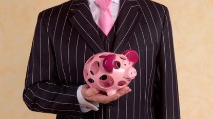 Man in a suit and tie holding a piggy bank that is full of holes