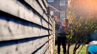 Garden laws you could be breaking - woman painting fence