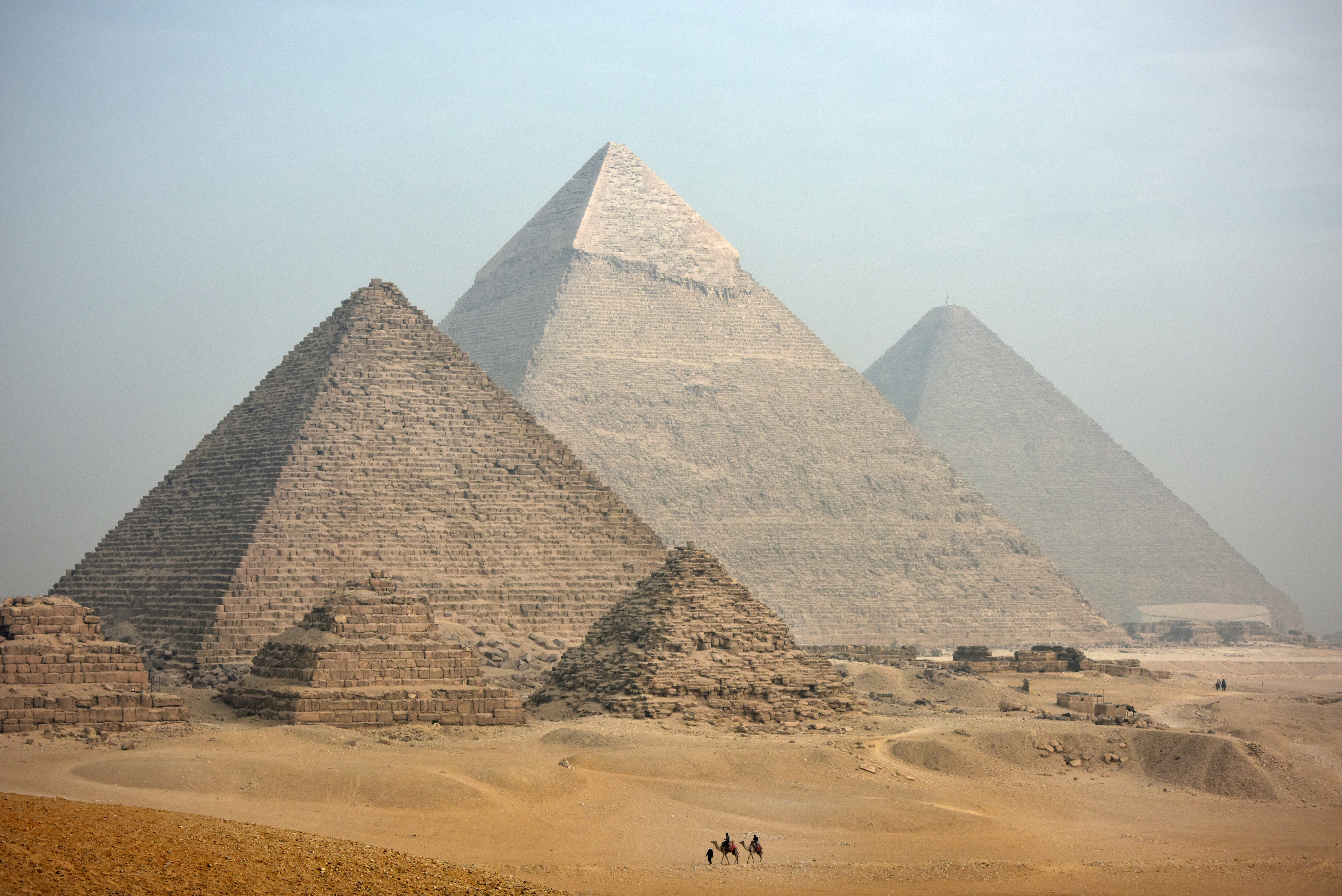 A distant camel caravan passes the majestic pyramids at Giza in Cairo at dusk