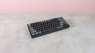 Three-quarter view of Keychron K2 Ultra 8K on a desk with pink wall in background