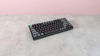 Three-quarter view of Keychron K2 Ultra 8K on a desk with pink wall in background