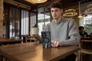 Man in grey jumper using phone in ESR case propped up on a table