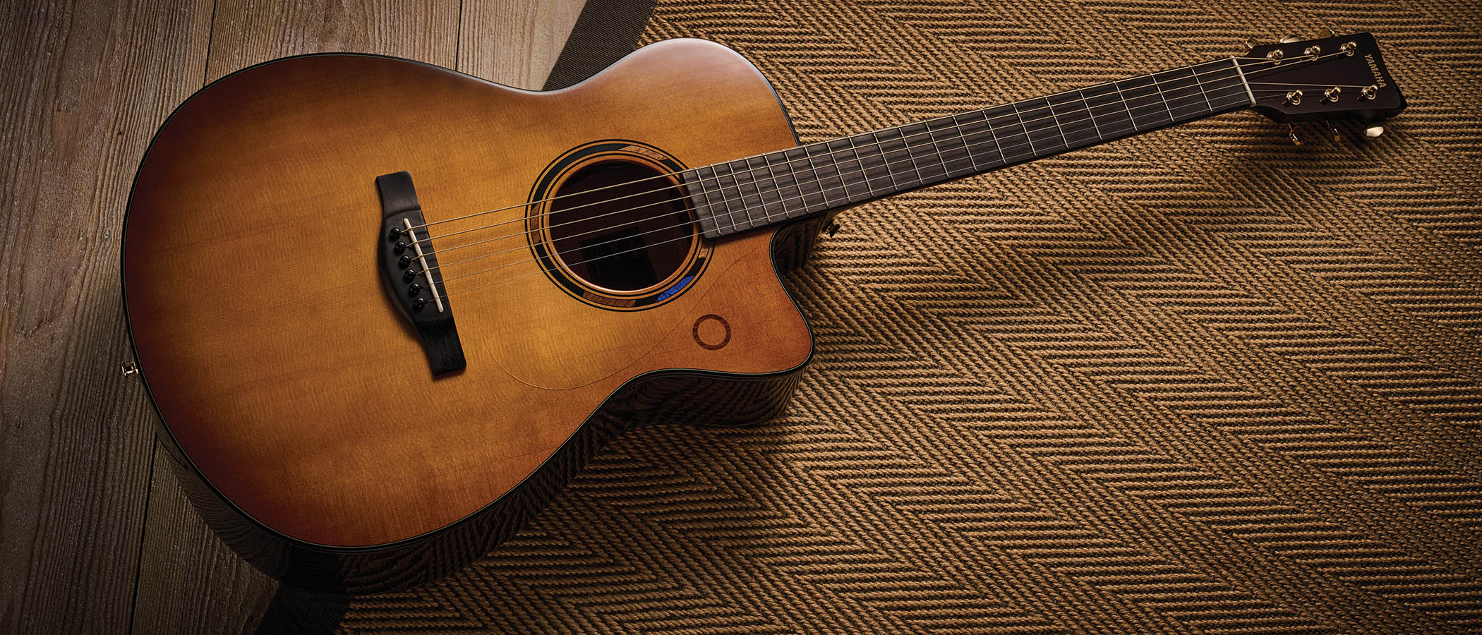 The Yamaha TransAcoustic TAG3 C is a cutaway acoustic guitar with a sandburst finished, photographed in closeup 