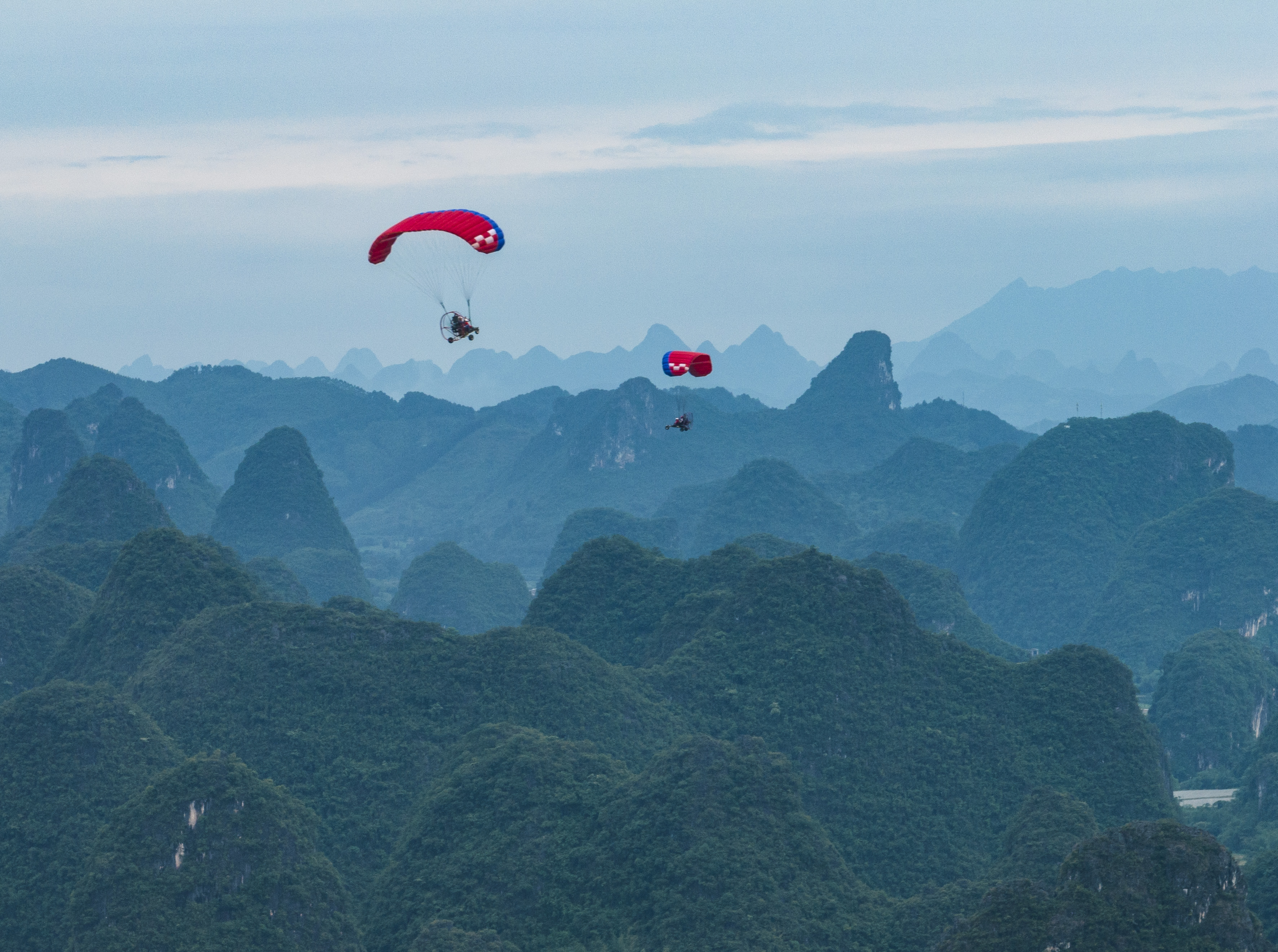 People paraglide over the green hills of Yangshuo in China